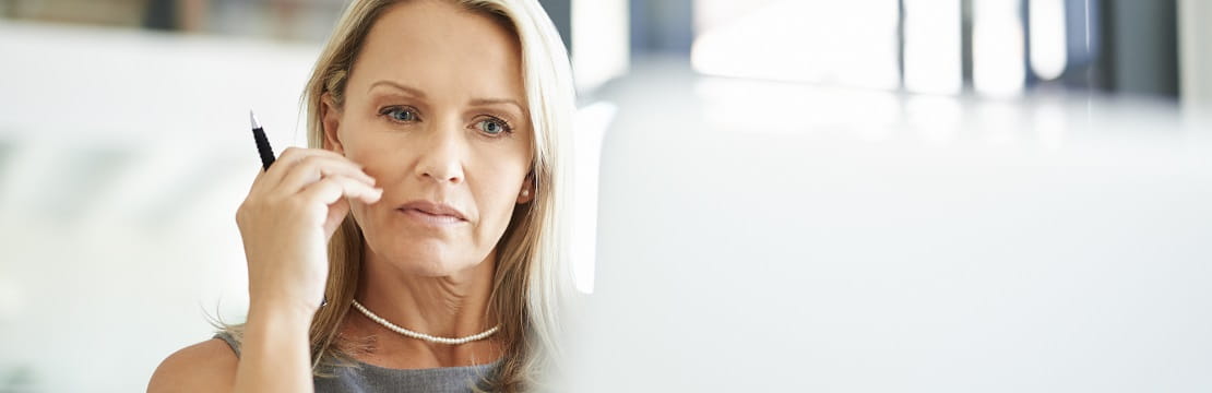 Woman looks at a laptop screen in an office setting.